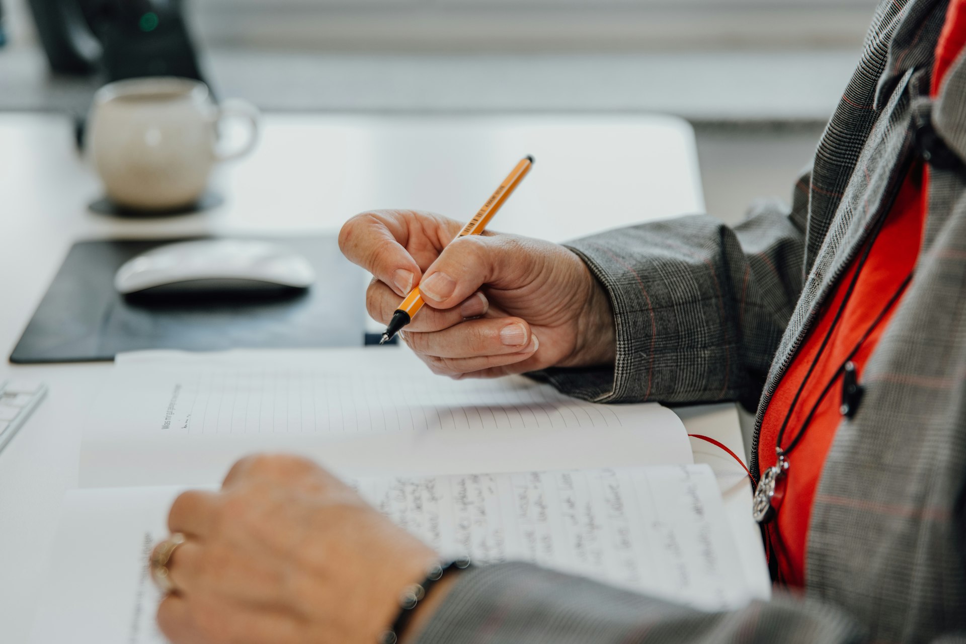 a person sitting at a desk writing on a piece of paper